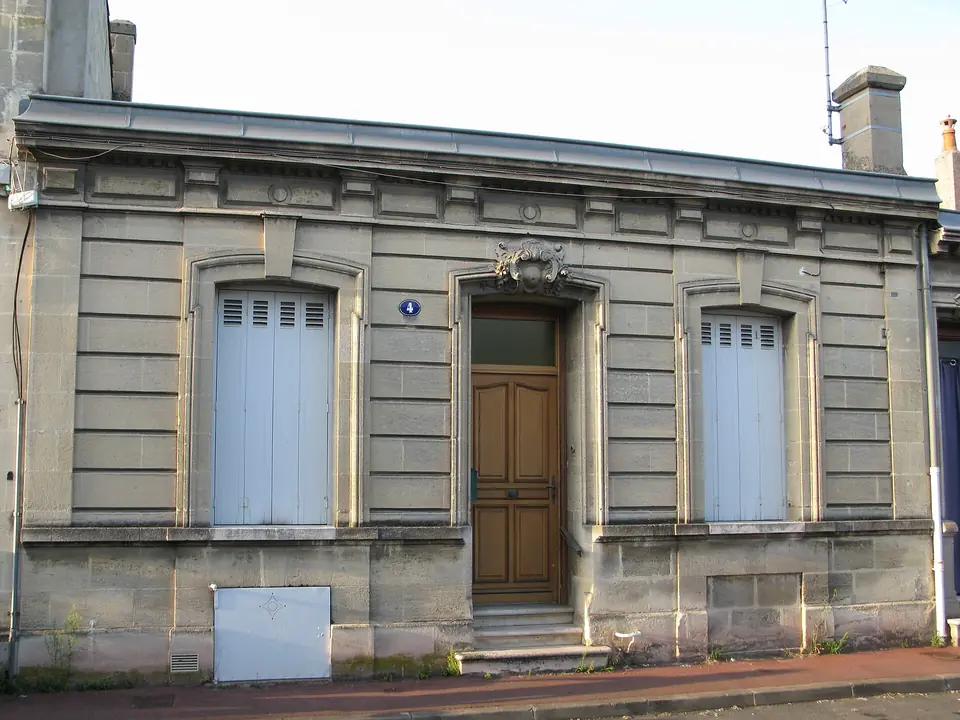 Échoppe bordelaise double à Talence, façade en pierre de taille claire avec porte d'entrée centrale en bois et volets persiennés clairs.